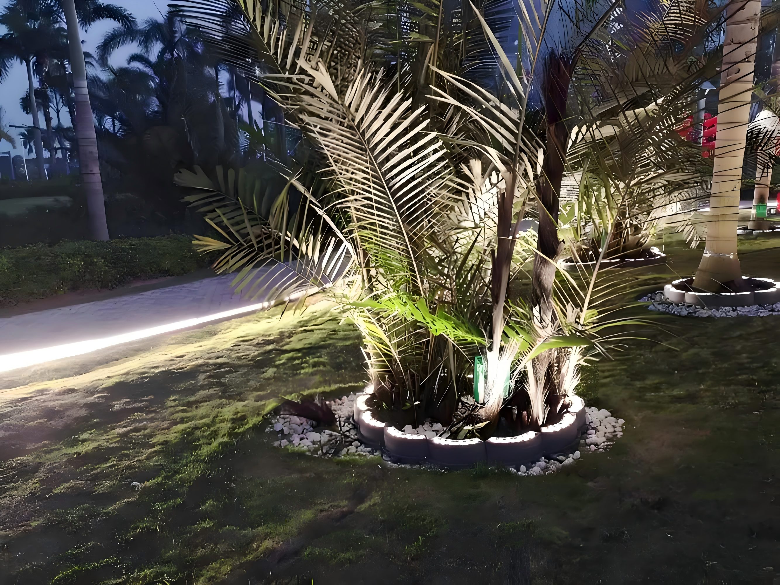 City boulevard at night showing multiple IP67 LED circular tree rings on median trees guiding pedestrians