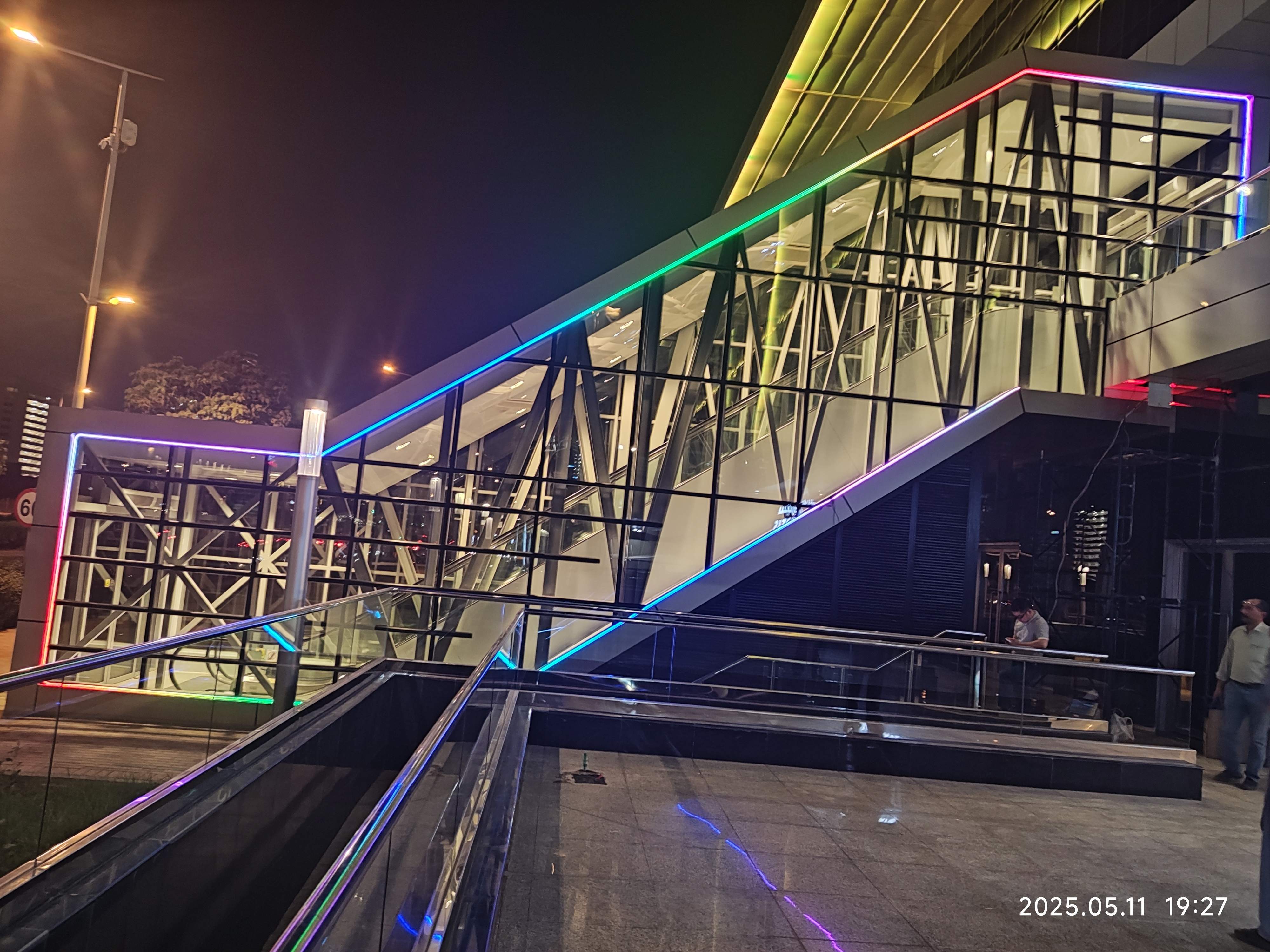 RGB linear lighting integrated into glass and steel architectural walkway structure at night