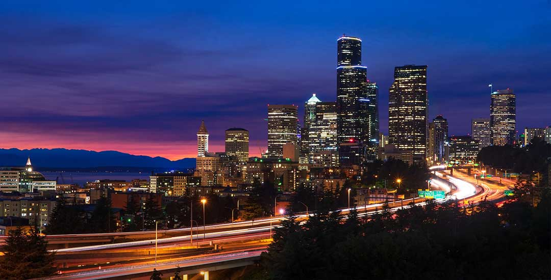 Seattle skyline at dusk with highway light trails in the foreground and colorful sky — façade lighting, urban façade illumination, architectural façade lighting, exterior LED lighting, façade lighting design